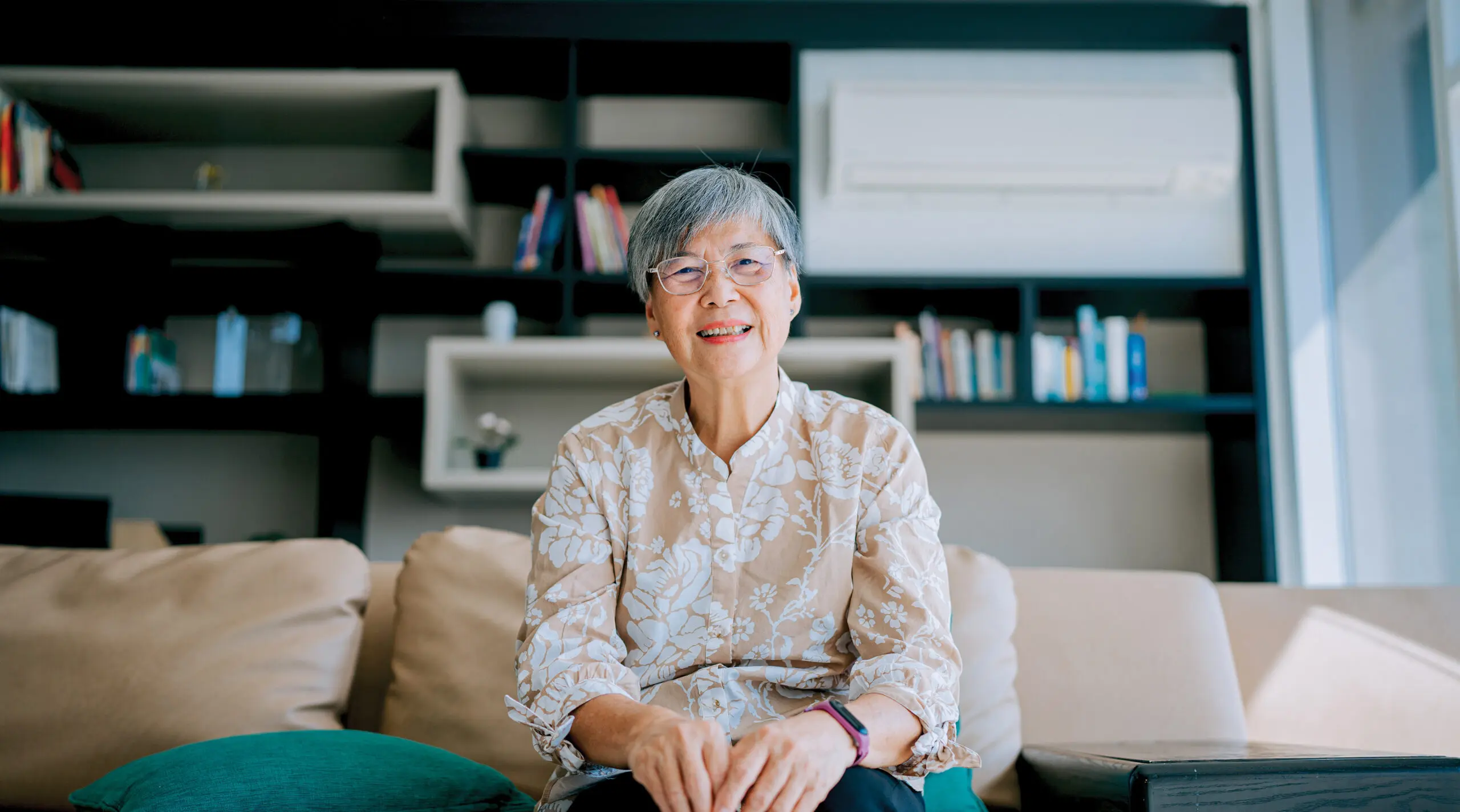 Senior woman sitting on a sofa, looking at the camera and smiling